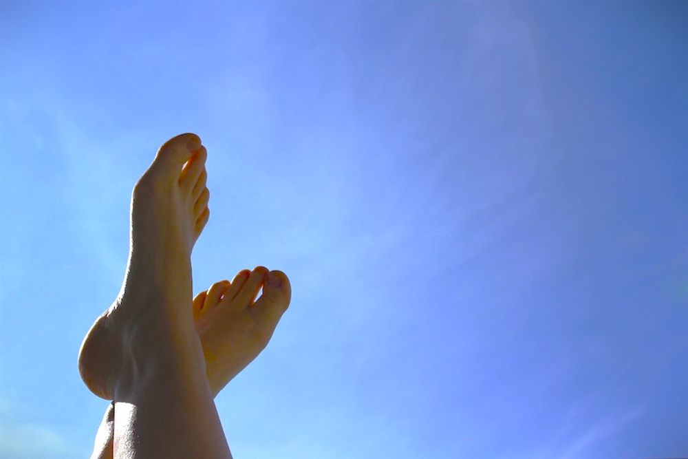 Bare feet raised against a blue sky